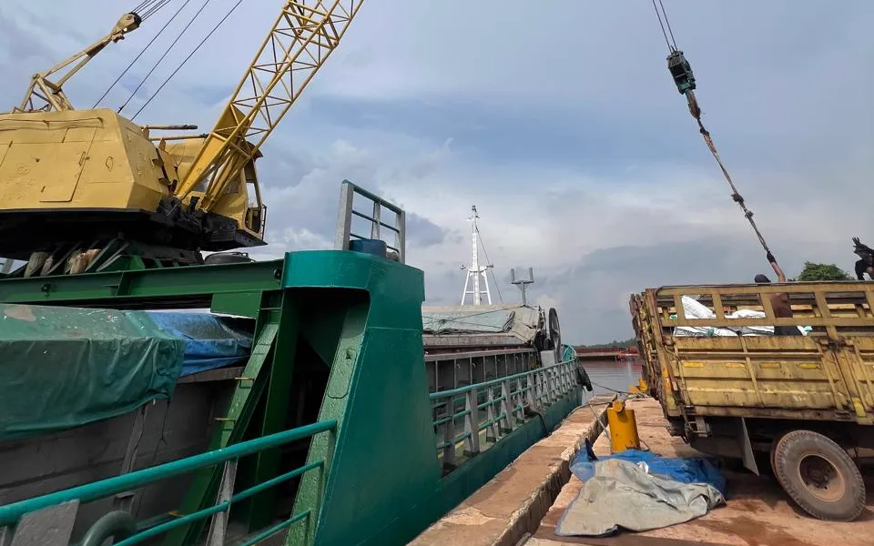 Crane loading Palm Kernel Expeller onto a barge at an Indonesian port